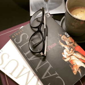 dois livros do autor. sobre eles, um par de óculos e, ao lodo, uma xícara de café