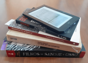 pilha com quatro livros e encimando, um leitor digital