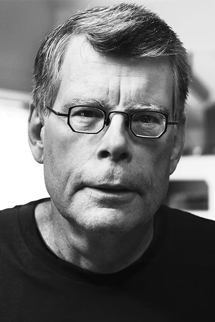 Autor de frente para câmera usando óculos em uma foto preto e branco